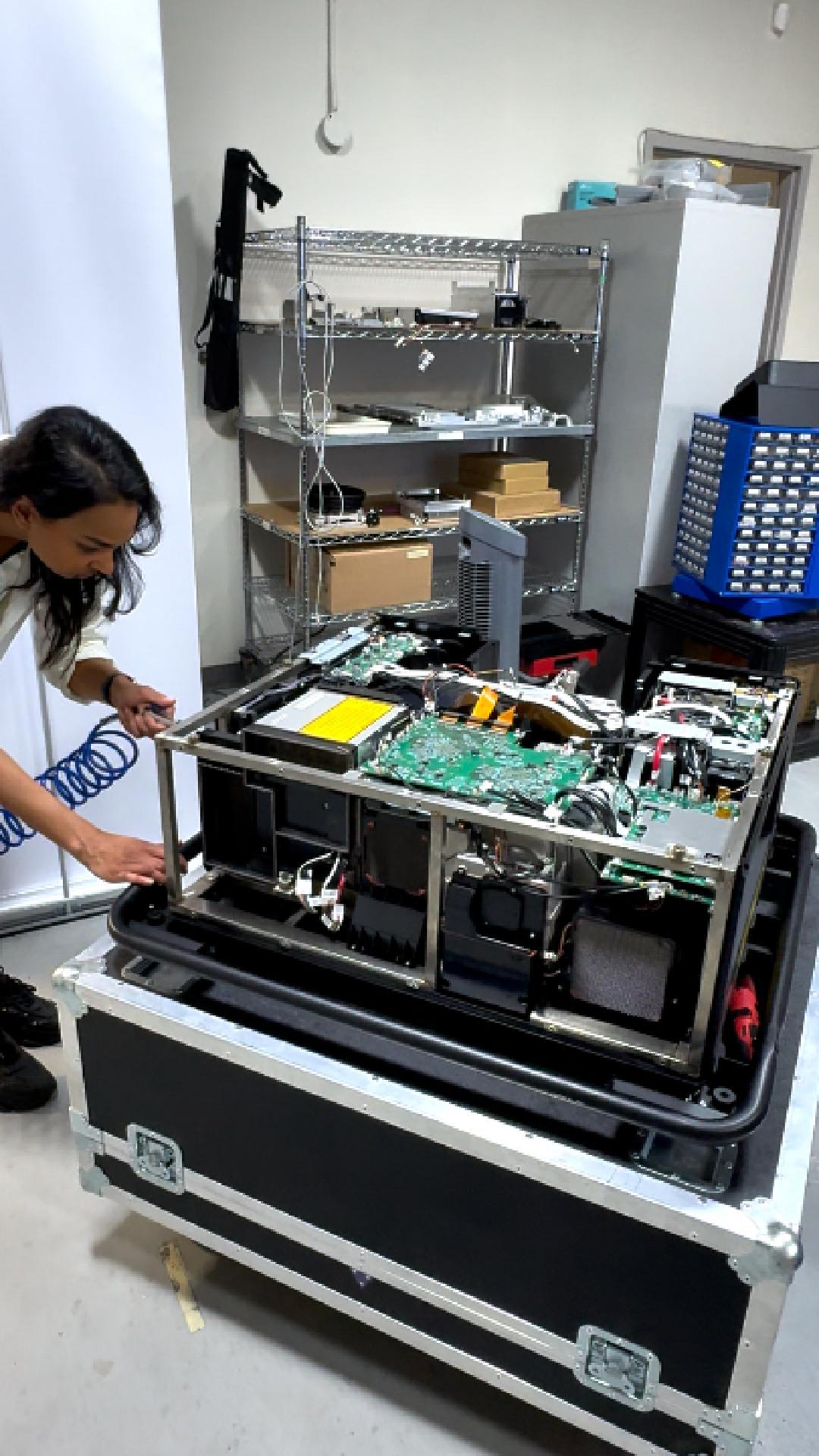 Technician working on projector hardware in a service workshop