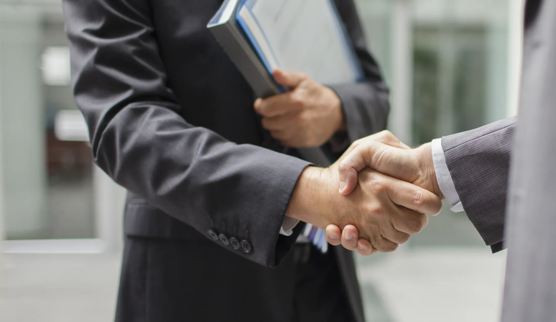 Two people in business attire shaking hands in a modern office